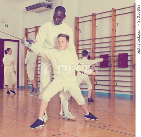 Fencing instructor with young fencers in training room Fencing instructor with young fencers in training room 53010655