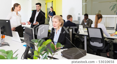 Coworkers engaged in open plan office Coworkers engaged in open plan office 53010658