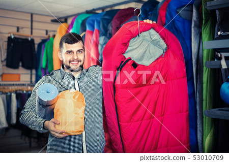 Man choosing touristic equipment in sports equipment store 53010709