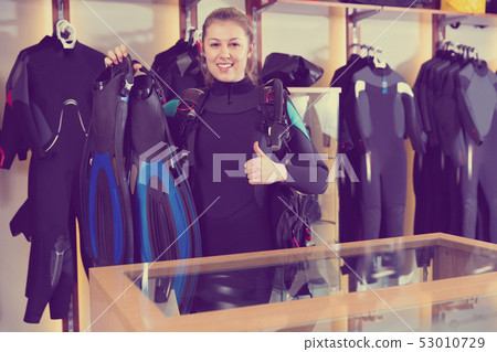 Sporty woman is satisfied of full set diving equipment in the diving store. 53010729