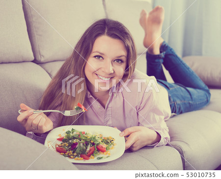 Smiling woman trying to eat tasty green salad 53010735