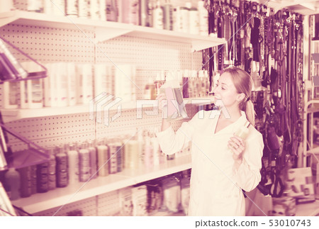 Young female shop assistant offering shampoo Young female shop assistant offering shampoo 53010743