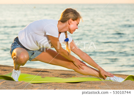 Woman in white T-shirt is practicing stretching Woman in white T-shirt is practicing stretching 53010744