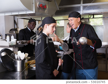 Exasperated chef scolding female employee Exasperated chef scolding female employee 53010745