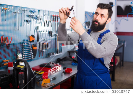 Man 25-35 years old is observing motorbike part for fixing 53010747