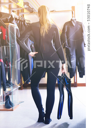 Sporty woman is posing in diving costume in the diving store. Sporty woman is posing in diving costume in the diving store. 53010748
