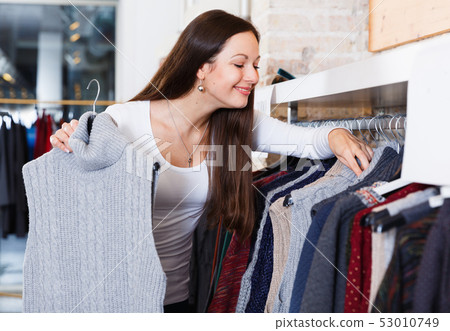 Positive adult woman buyer choosing sweater in shop Positive adult woman buyer choosing sweater in shop 53010749