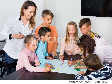 Children with teacher drawing together in classroom 53010875
