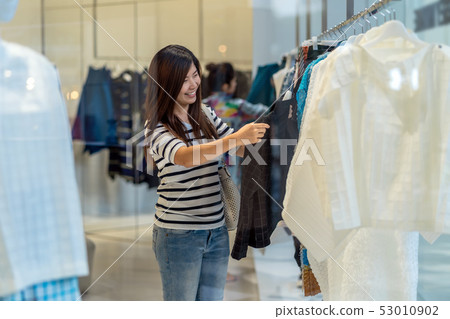Happy Asian woman choosing clothes in glass store shop with happy action at department center Happy Asian woman choosing clothes in glass store shop with happy action at department center 53010902