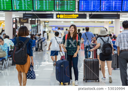 Asian traveler with luggage looking the flight board at the flight information screen check-in in modern an airport, travel and transportation with technology concept. 53010994