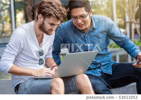 Couple colleague Of Asian and Multiethnic Business people with casual suit working with serious action at the outdoor public, people business group concept Couple colleague Of Asian and Multiethnic Business people with casual suit working with serious action at the outdoor public, people business group concept 53011052