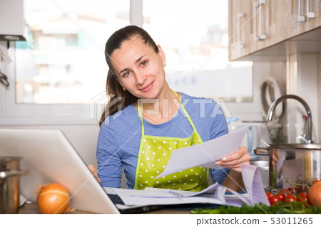 Woman filling papers and using laptop 53011265