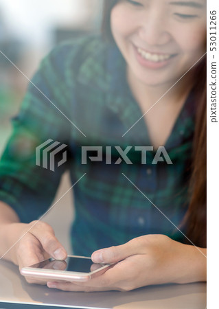 Closeup Asian businesswoman hand using the smart mobile phone with happiness action on the desk beside the glass in workplace or co-working space or modern office, business lifestyle concept 53011266