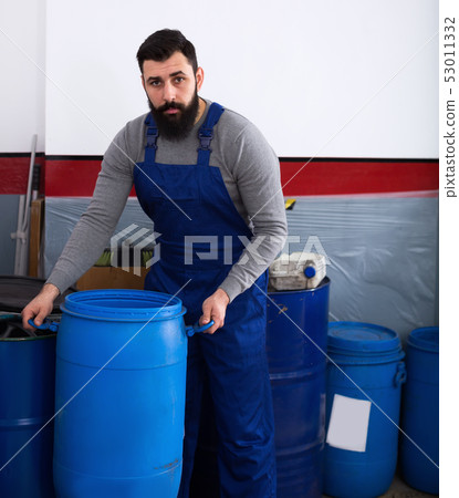 Worker transporting barrels in motorcycle workshop Worker transporting barrels in motorcycle workshop 53011332