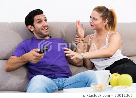 Couple on sofa quarreling because of TV remote 53011365