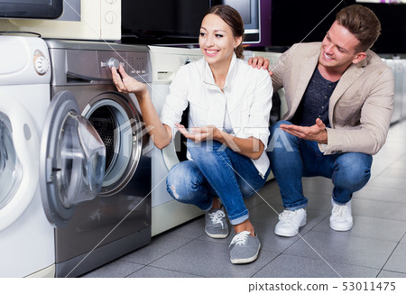 Positive customers looking at laundry machine 53011475