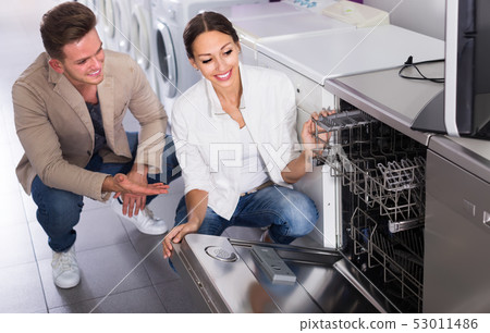 Ordinary young customers choosing new dish washing machine Ordinary young customers choosing new dish washing machine 53011486