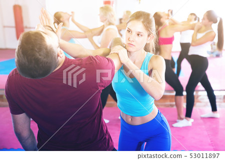 Sporty female with trainer are doing self-defence moves in gym 53011897