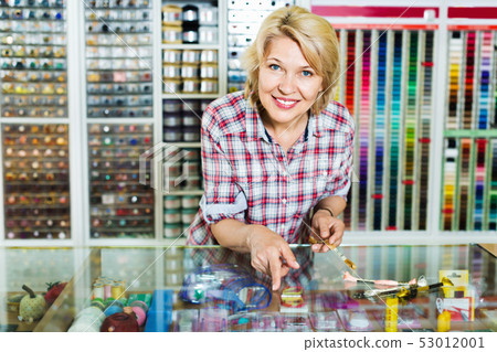 Mature glad woman seller is ready to help at cash desk Mature glad woman seller is ready to help at cash desk 53012001