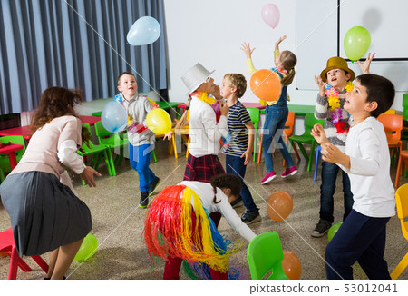 Pupils with teacher amusing with balloons Pupils with teacher amusing with balloons 53012041