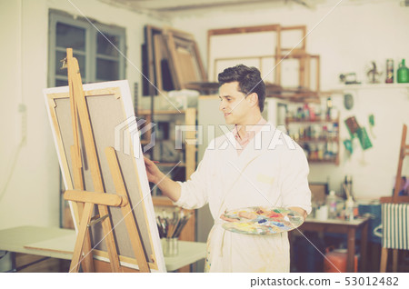 Man near easel painting on canvas Man near easel painting on canvas 53012482