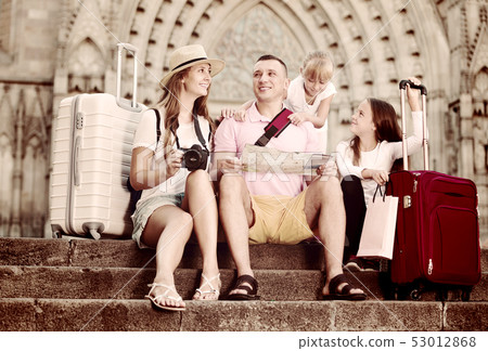 Happy family of fours tourists sitting on old cathedral steps Happy family of fours tourists sitting on old cathedral steps 53012868