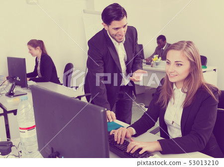 Bearded man flirting with woman working in office 53013210