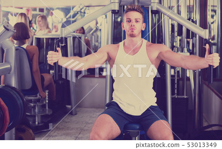 well trained man using pec deck gym machinery indoors well trained man using pec deck gym machinery indoors 53013349