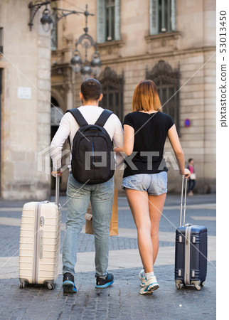 Young man and woman walking with baggage Young man and woman walking with baggage 53013450