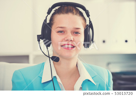 Office worker woman is working at a computer and talking by headset with client