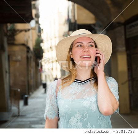 Young positive female in hat talking by phone in the historical city 53013758
