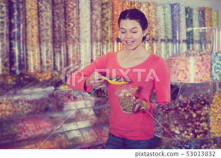 Shopgirl in store is picking up candies Shopgirl in store is picking up candies 53013832