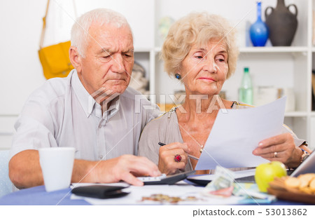 Serious retired couple calculating bills Serious retired couple calculating bills 53013862