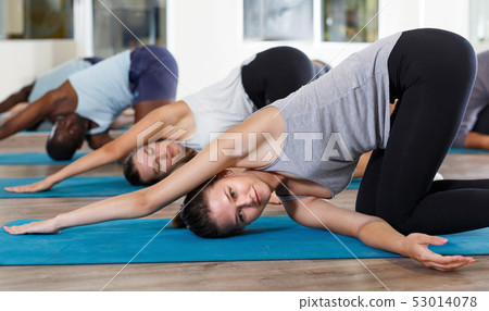 Group of active women and men doing stretching workout at gym 53014078