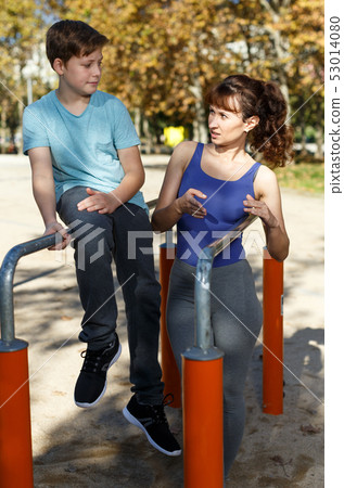 Family exercising on parallel bars outdoors 53014080