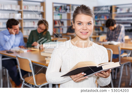 female student browsing textbooks in university library 53014203