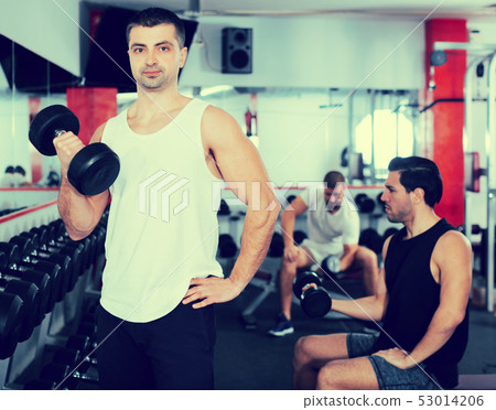 Man exercising with dumbbells in gym Man exercising with dumbbells in gym 53014206