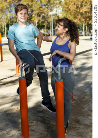 Family exercising on parallel bars outdoors Family exercising on parallel bars outdoors 53014208