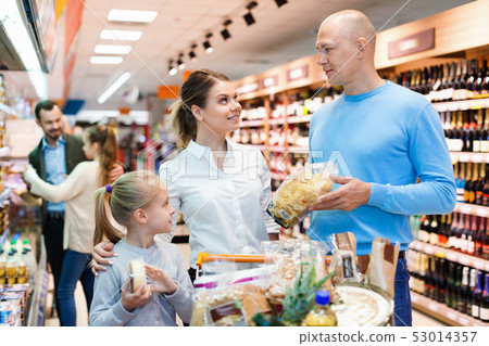 Family is looking on shelves with products in the supermarket. 53014357