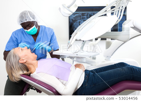 Mature female patient sitting in dental chair. Dentist is treating female patient 53014456