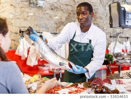 Salesman serving customer raw fish 53014633