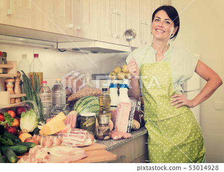 Cheerful woman is posing in time cooking on the kitchen Cheerful woman is posing in time cooking on the kitchen 53014928