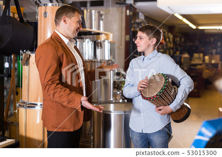 Smiling father and son examining ethnic drums 53015300