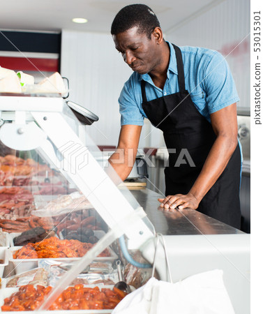 African American seller preparing fresh meat of lamb for sale in butcher store African American seller preparing fresh meat of lamb for sale in butcher store 53015301