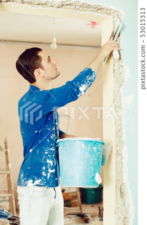 Plasterer renovating indoor doorway Plasterer renovating indoor doorway 53015313