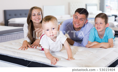 Small client with his happy family choosing right mattress in home furnishings store Small client with his happy family choosing right mattress in home furnishings store 53015404