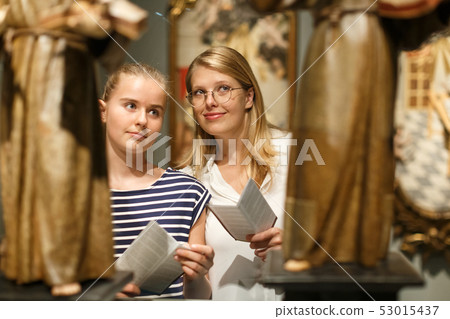 Portrait of woman visitor with daughter looking at exhibition in museum 53015437