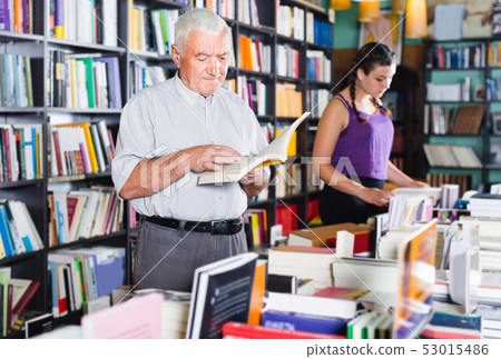 Old male is choosing book for reading in free time in bookstore. Old male is choosing book for reading in free time in bookstore. 53015486