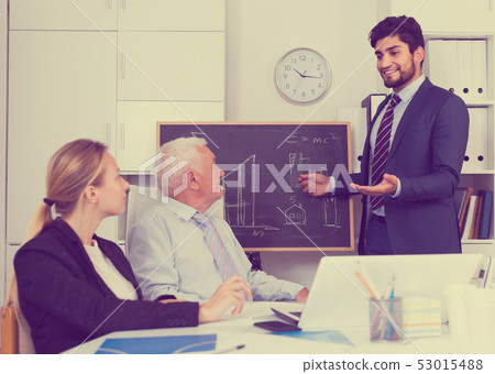 Office manager male is reading financial report to colleagues on meeting 53015488