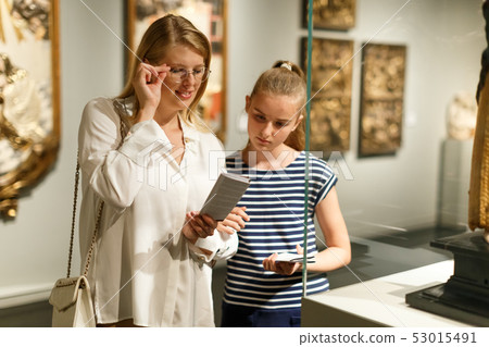 Girl with woman looking with interest at art objects in museum 53015491